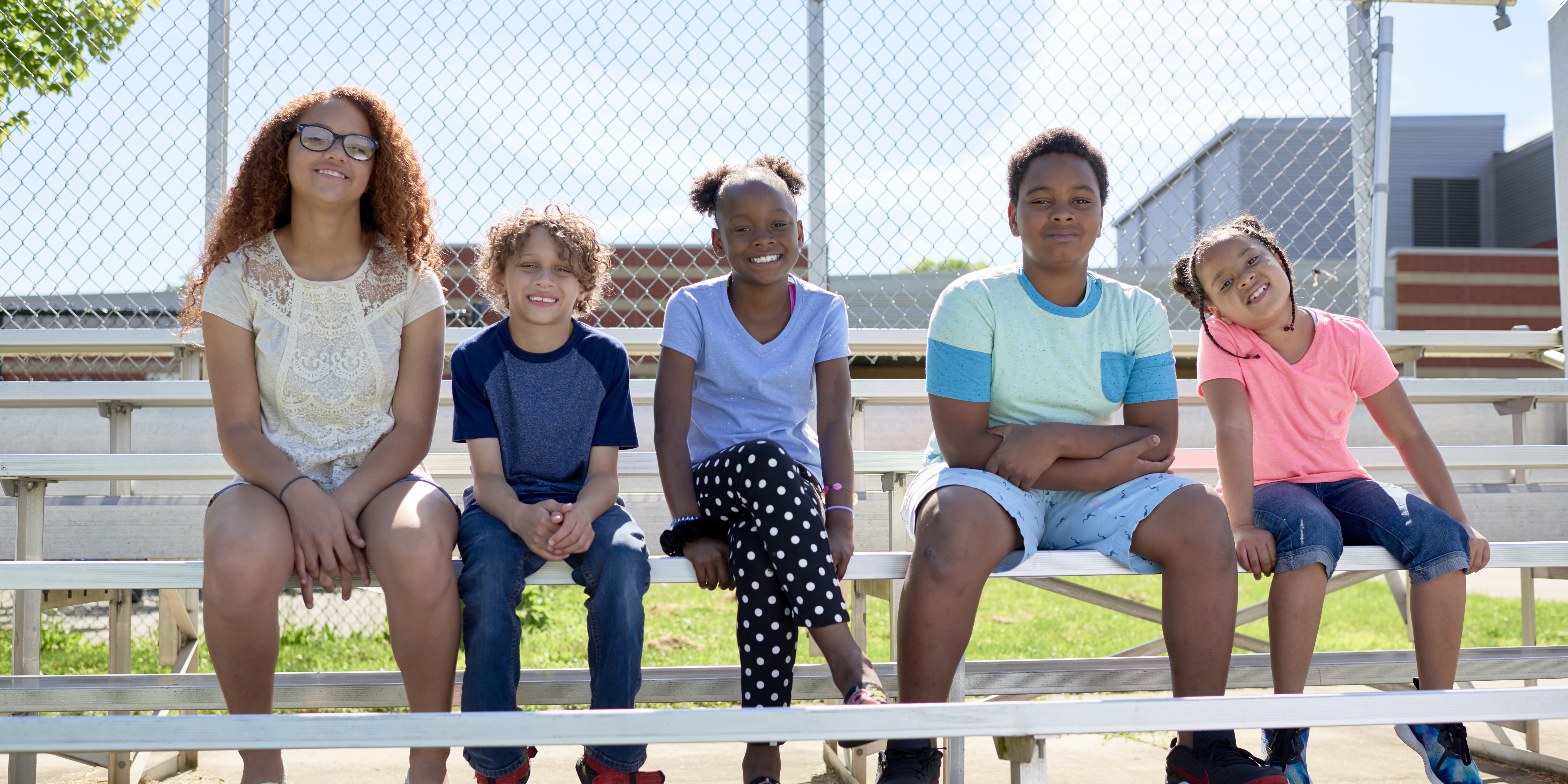 Local kids sitting on metal bleachers at school.