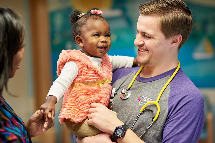 Smiling nurse holding a young child.