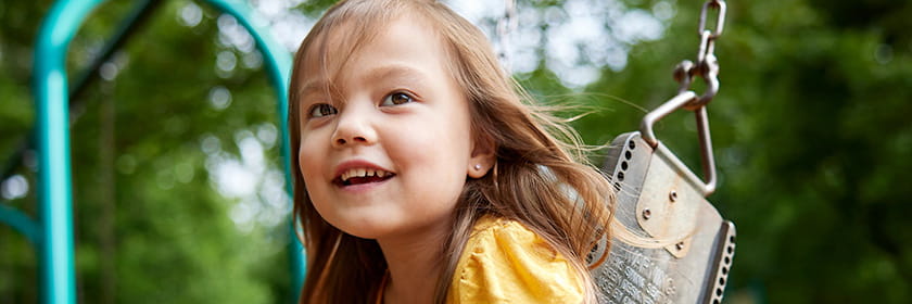 Child smiling while swinging at the park.