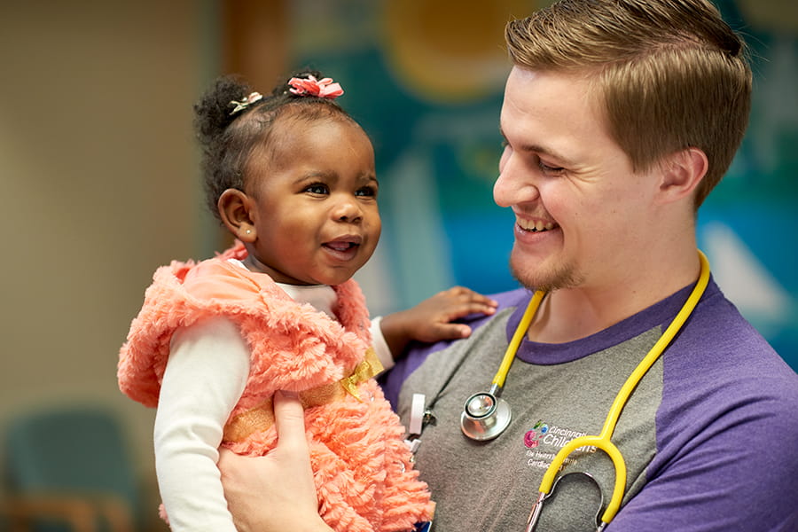 Nurse holding a smiling infant.