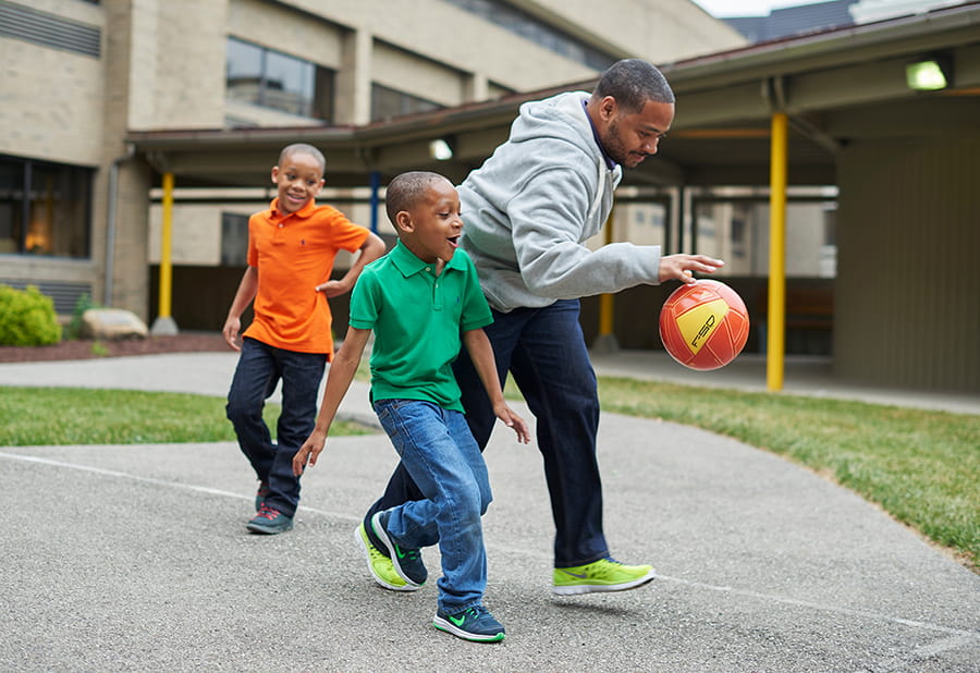 Adult playing basketball with young patients.