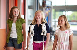 Three sisters smiling, one on crutches.