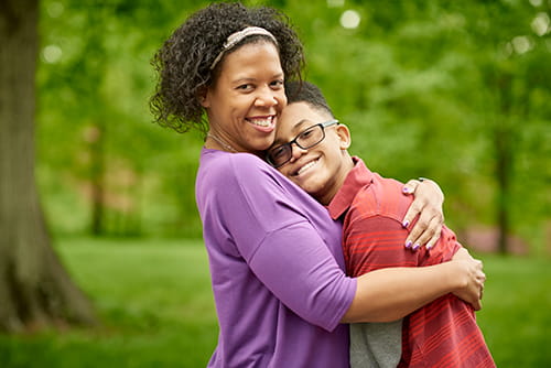 Mother hugging teenage son.