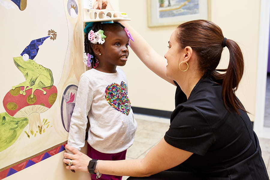 Nurse taking height measurements of young girl.