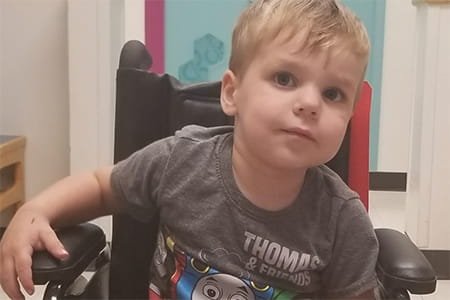 Carson, a fibular deficiency patient, sitting in a wheel chair.