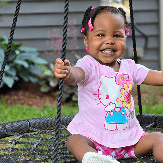 Journey smiles on a swing.