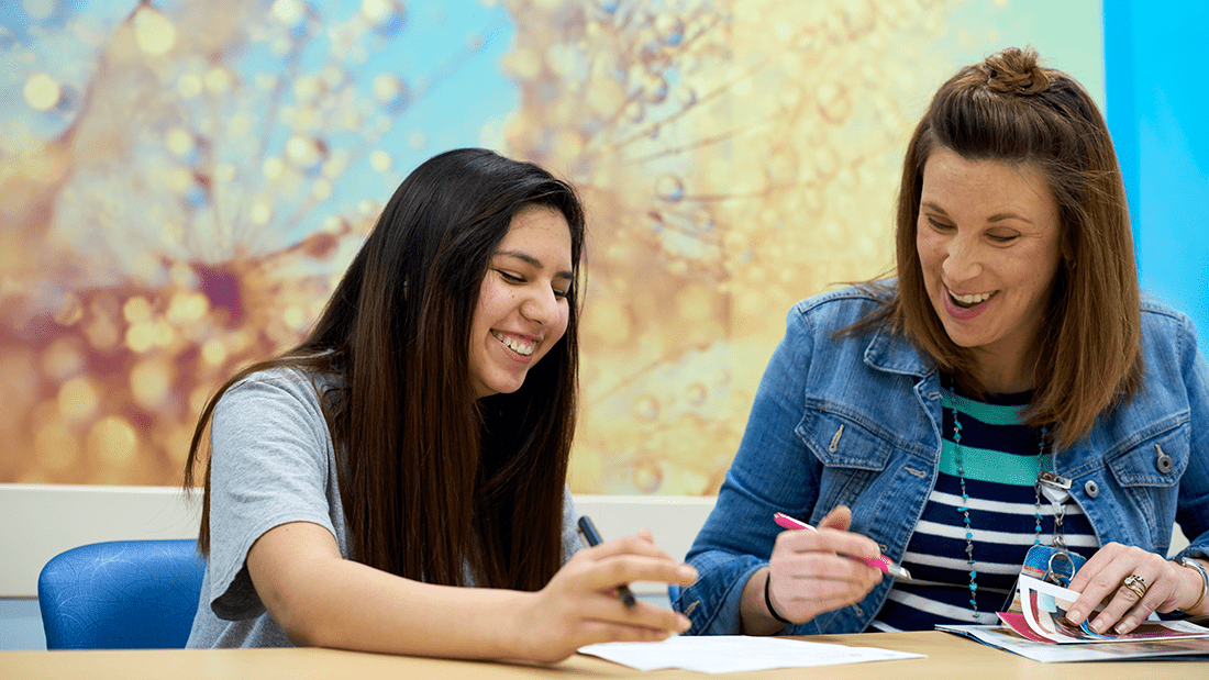 A girl and a woman sitting together at a table.