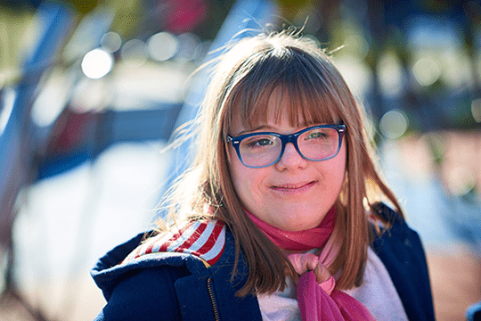 Down syndrome patient smiling while playing outside in the fall.
