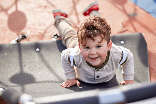 A boy smiling while playing outside.