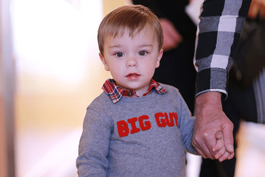 A toddler holding his grandpa's hand.