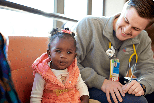 Male nurse and infant smiling during initial evaluation.