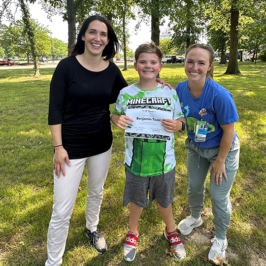 Ben smiles with sports camp certificate.