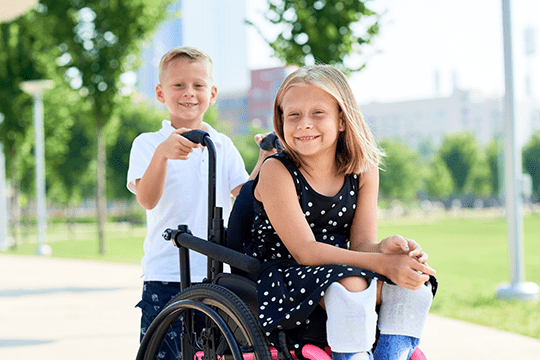 Two siblings smiling while playing outside.