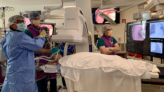 Doctors work on a patient inside the hybrid operating room.