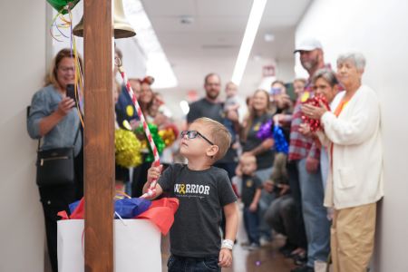 Owen, a patient of the Retinoblastoma Program, rings the bell at the end of his cancer treatment.