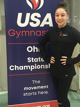 Claire next to USA Gymnastics sign.