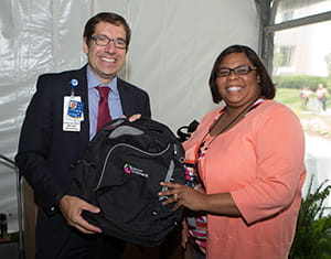 Derek Wheeler, MD, Chief of Staff, gives a backpack to Melissa Arrington, specialist, Human Resources, who stopped by on her lunch break.